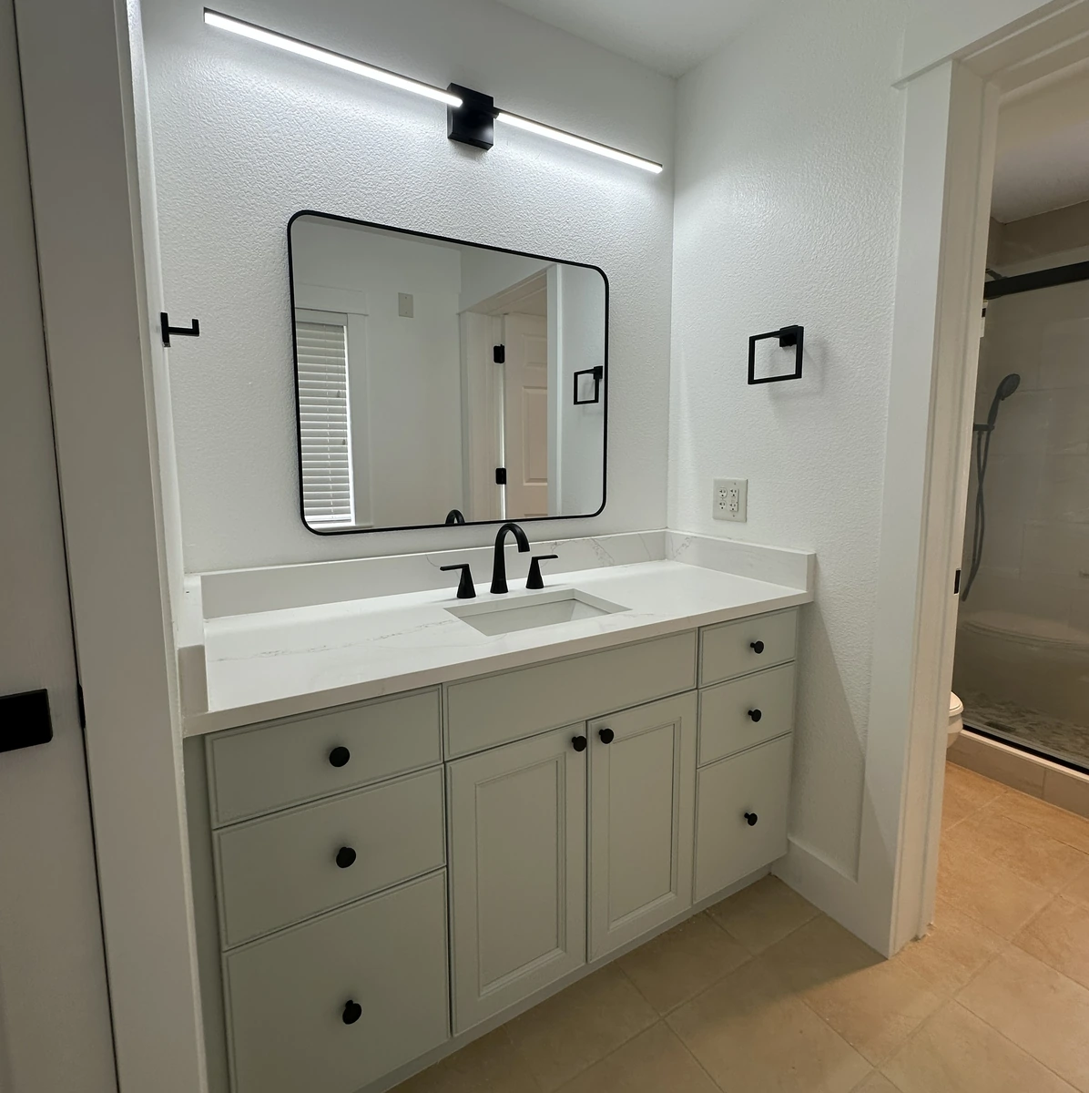Remodeled guest bathroom with a wide mirror by Guy A Remodeling