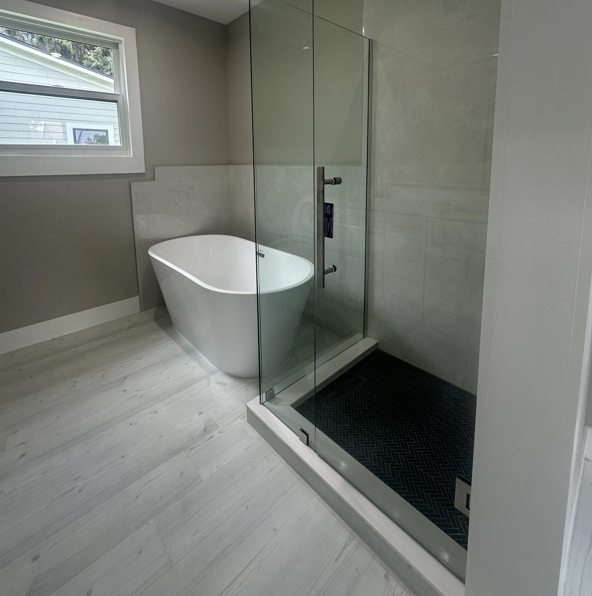 Remodeled bathroom with a freestanding soaking tub by Guy A Remodeling