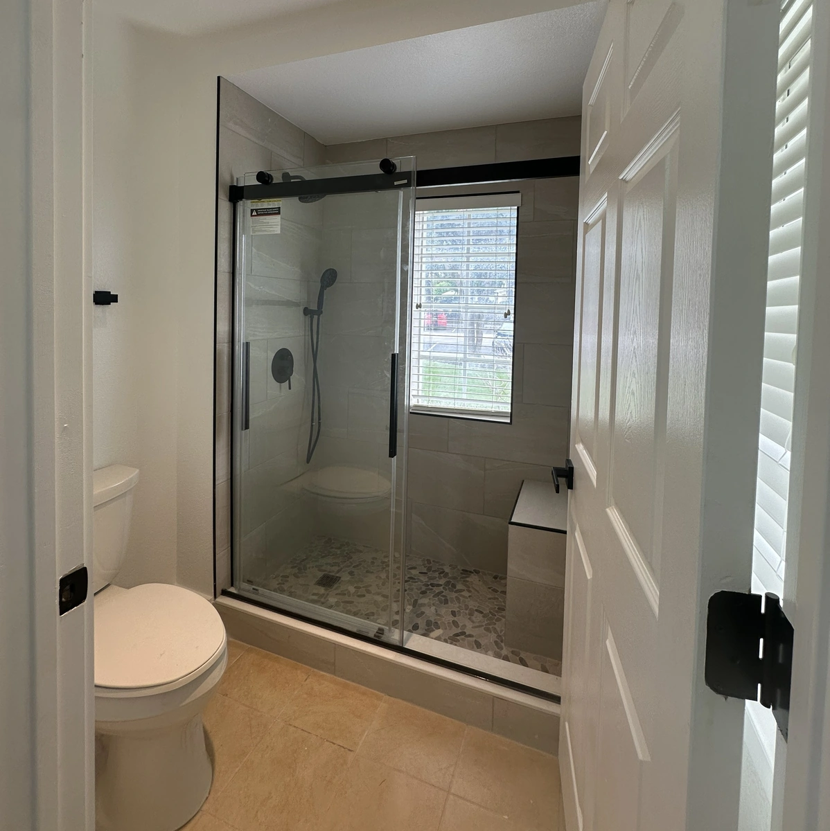 Remodeled St. Cloud bathroom with a tiled walk in shower and a river stone floor by Guy A Remodeling