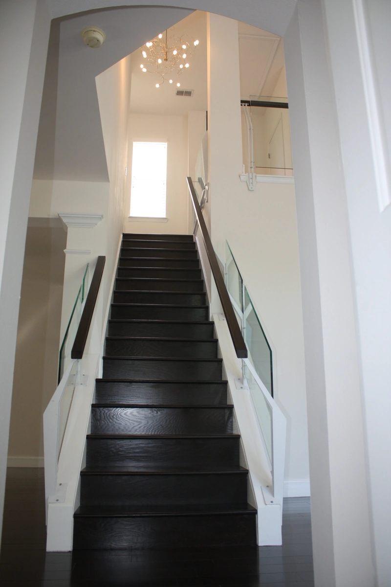Remodeled stairway with a chandelier by Guy A Remodeling