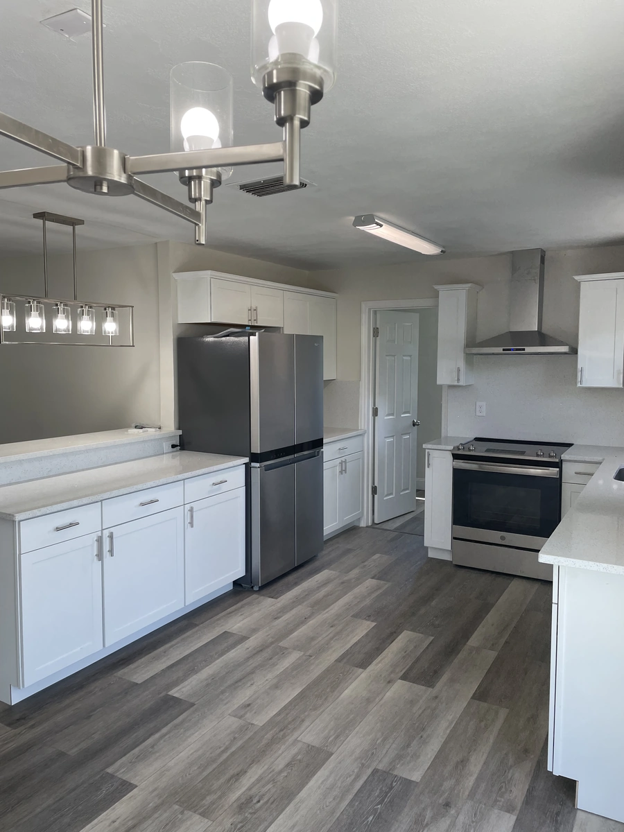 Finished Lakeland ranch kitchen with white cabinets, pendant lights, and a sliding glass door