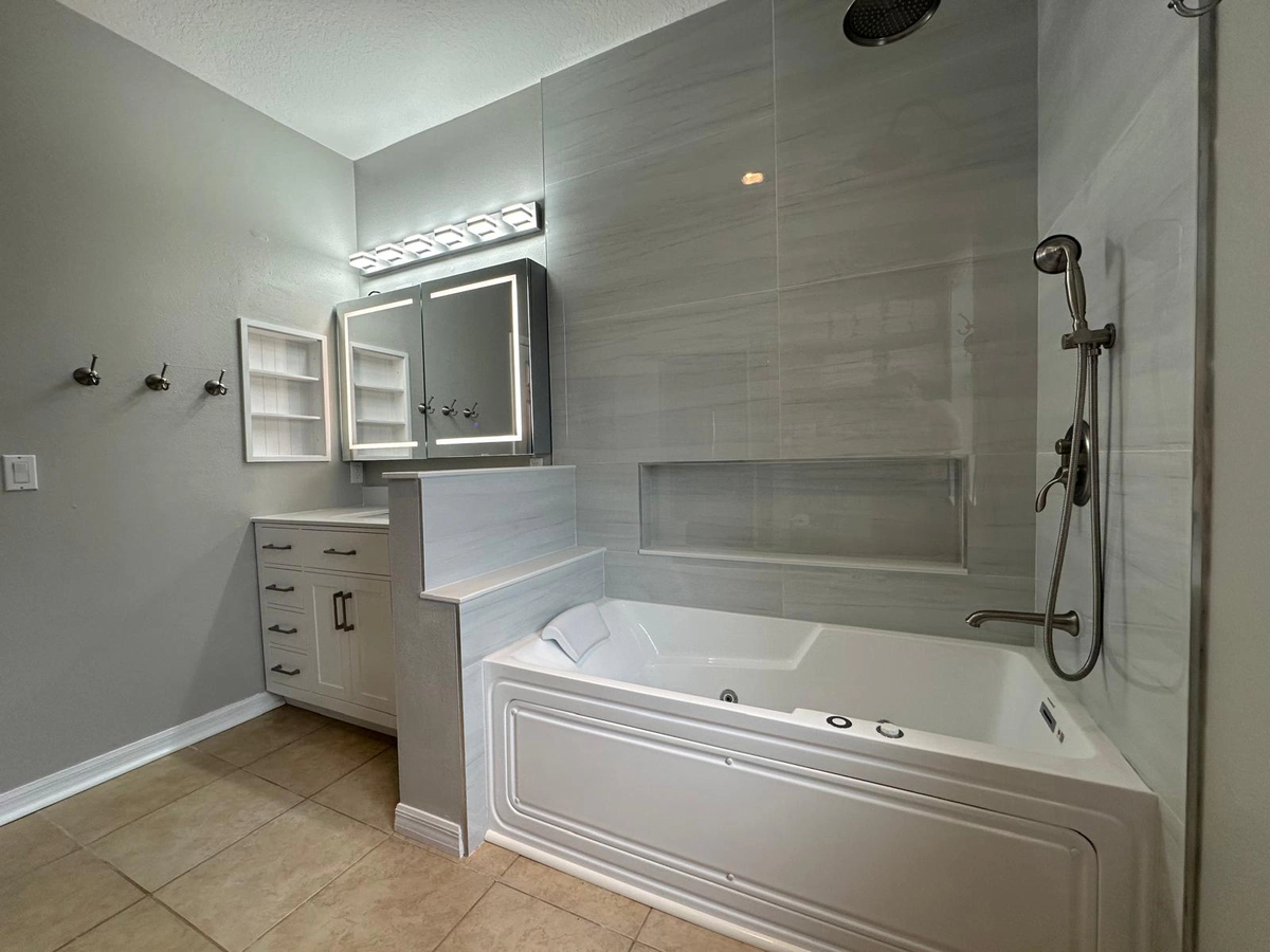 The finished Jacuzzi tub in the Celebration bathroom, with its jets, a tiled niche above it, and a hand shower on a slide bar