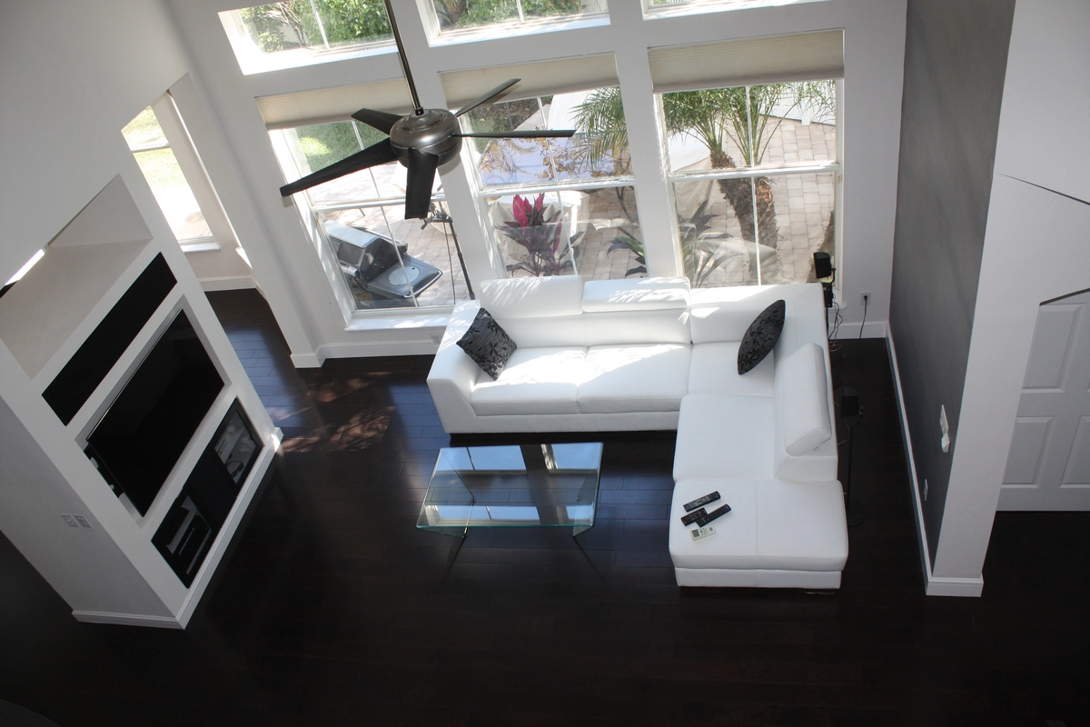 Finished Kissimmee living area with tall windows, high ceilings, and dark wood floors by Guy A Remodeling