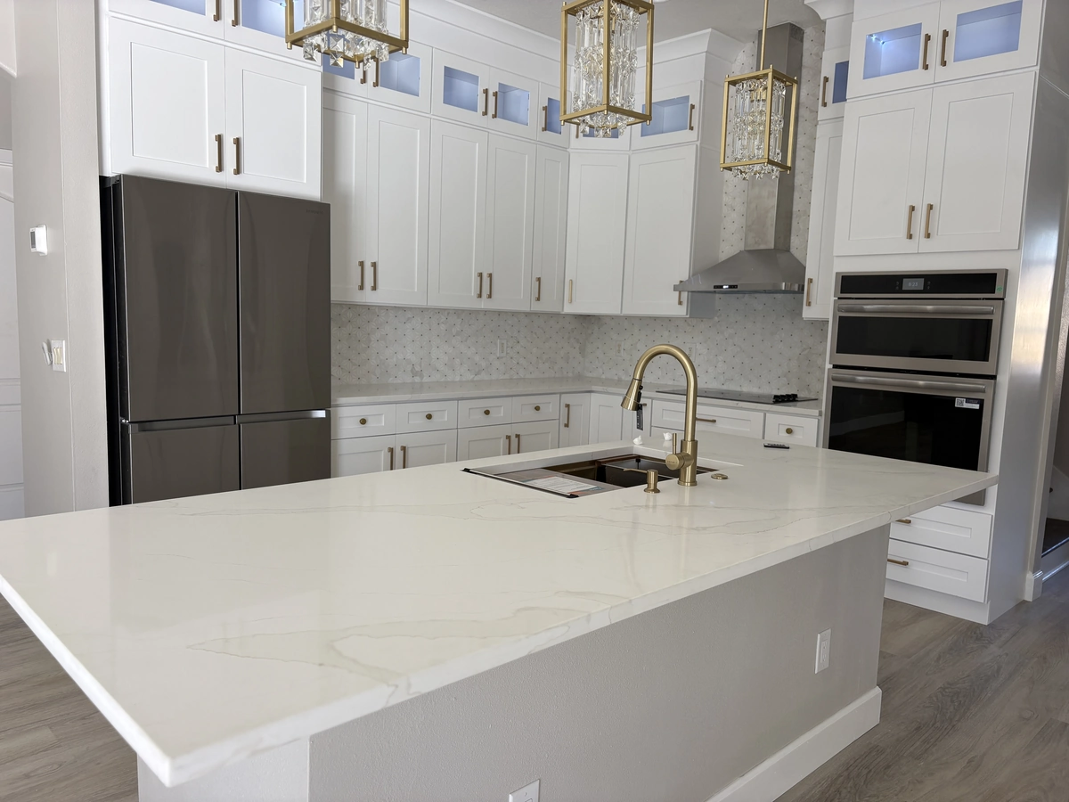 Finished Davenport kitchen with white cabinets, a marble island, and gold glass chandeliers by Guy A Remodeling