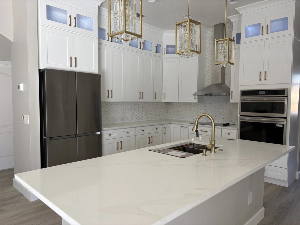 Remodeled Davenport kitchen island in white quartz with a gold faucet and stainless appliances by Guy A Remodeling