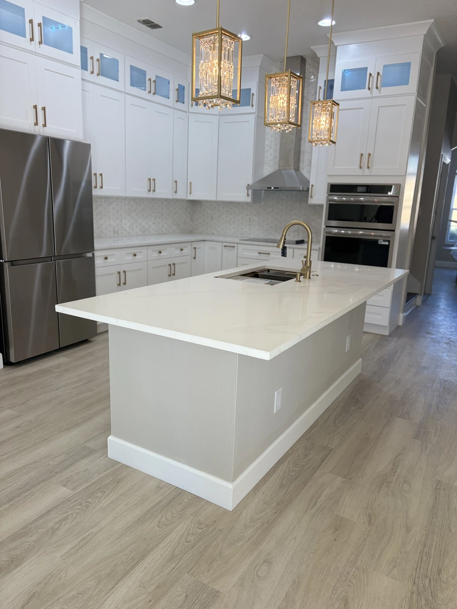 Finished Davenport kitchen with a large white island, gold chandeliers, and wood look flooring