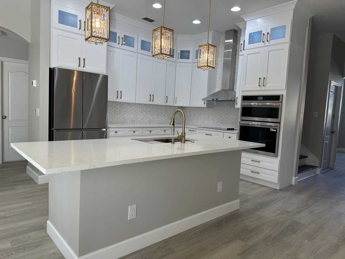 Remodeled Davenport kitchen with a long quartz island, white cabinets, and glass and brass chandeliers by Guy A Remodeling