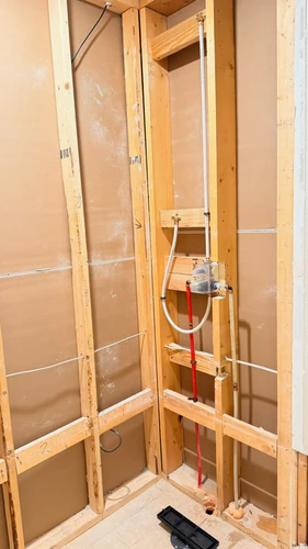 The shower wall opened to the studs, with new PEX supply lines, a new valve body, and the niche framed in
