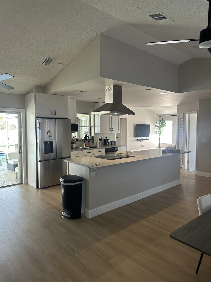 Finished open concept Orlando kitchen with a modern gray island and white cabinets by Guy A Remodeling