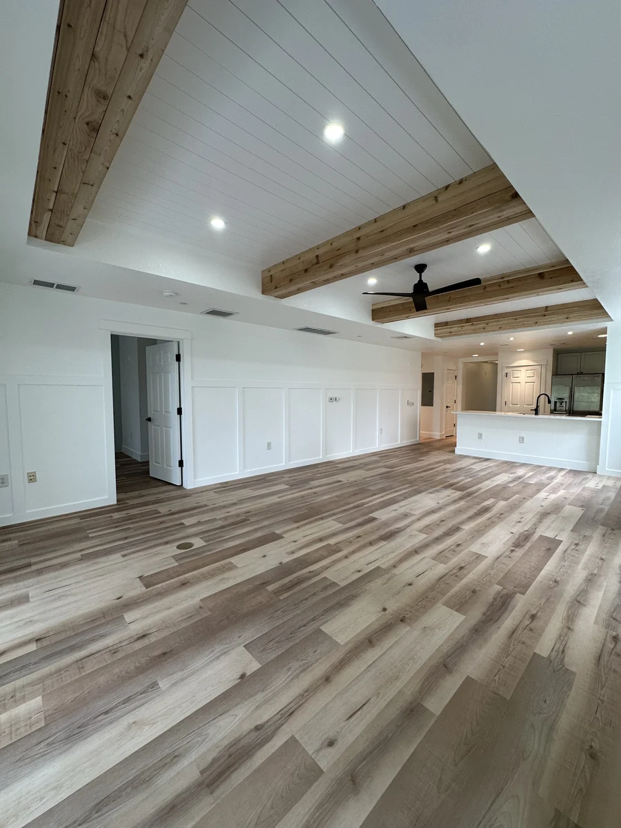 Finished open living and kitchen in Kissimmee with wood beams, a shiplap ceiling, and wood floors by Guy A Remodeling