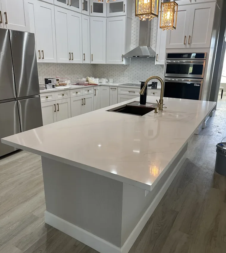 Finished Davenport kitchen with a long white quartz island and gold pendant lighting by Guy A Remodeling