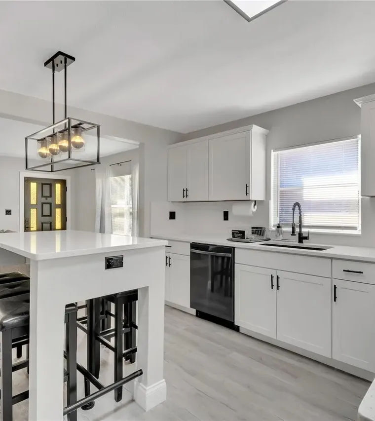 Remodeled St. Cloud kitchen with a white island, pendant lighting, and black bar stools by Guy A Remodeling