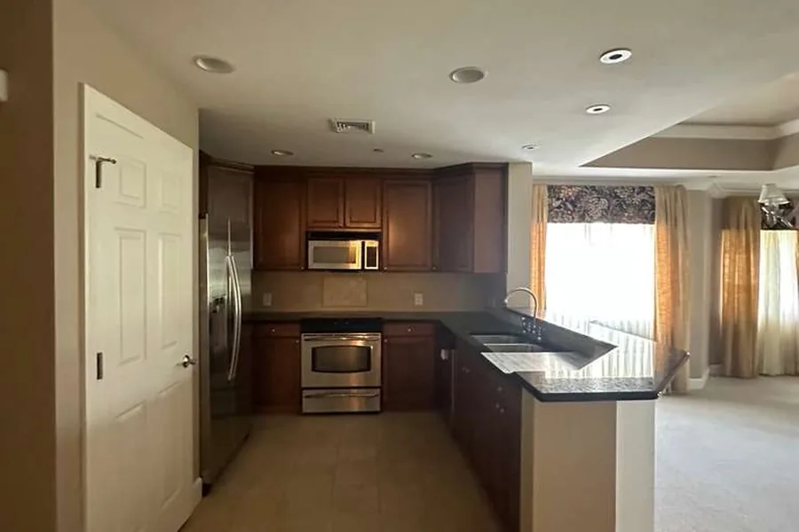 Dated kitchen with dark wood cabinets and black counters before remodeling by Guy A Remodeling