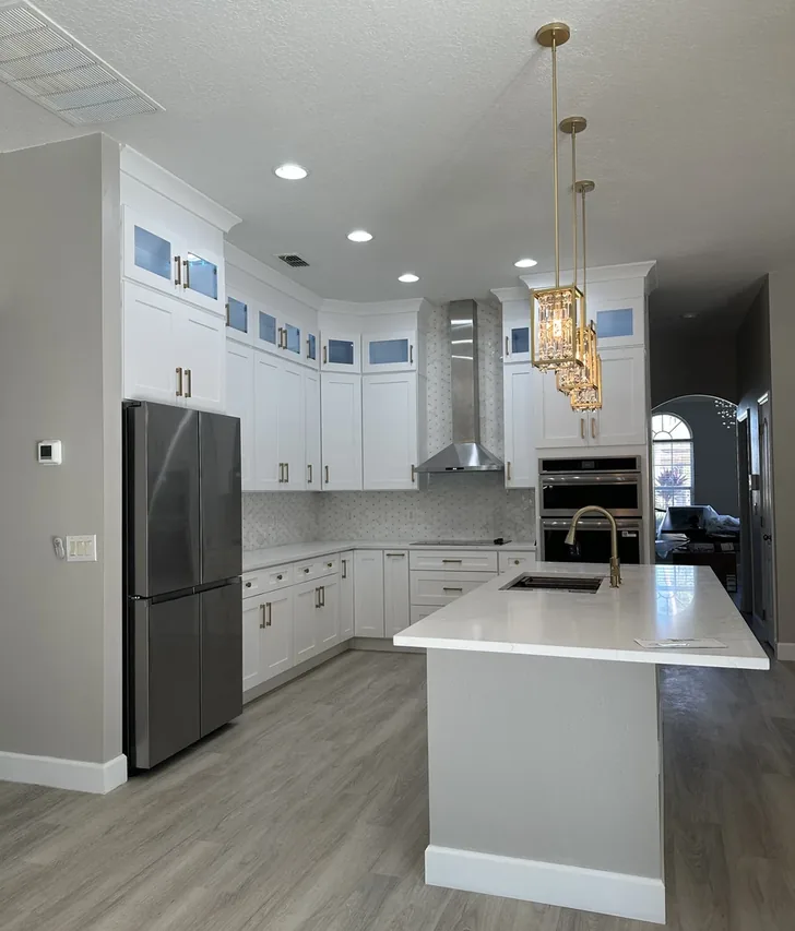Remodeled Davenport kitchen with white cabinets, gold pendant lights, and a quartz island by Guy A Remodeling