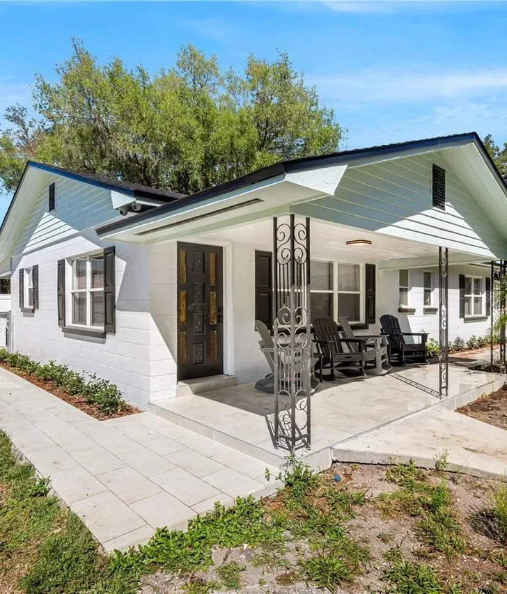 Freshly remodeled white single story home in Kissimmee with a covered front porch and new landscaping by Guy A Remodeling