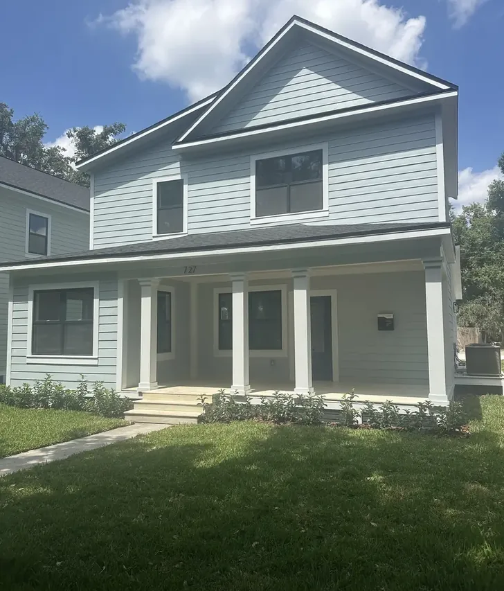 Remodeled two story Lakeland home with light siding, a covered front porch, and new landscaping by Guy A Remodeling