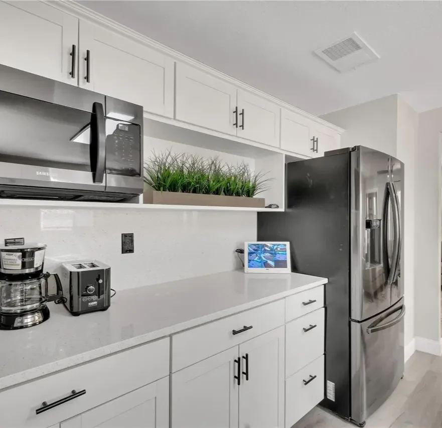 Remodeled Orlando kitchen with white shaker cabinets, a stainless steel refrigerator, and quartz counters by Guy A Remodeling